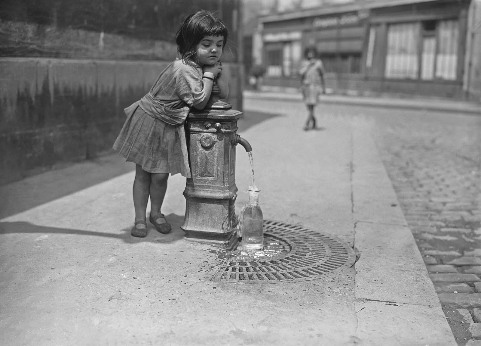 Une fillette boit à une borne-fontaine pendant une vague de chaleur à Paris
