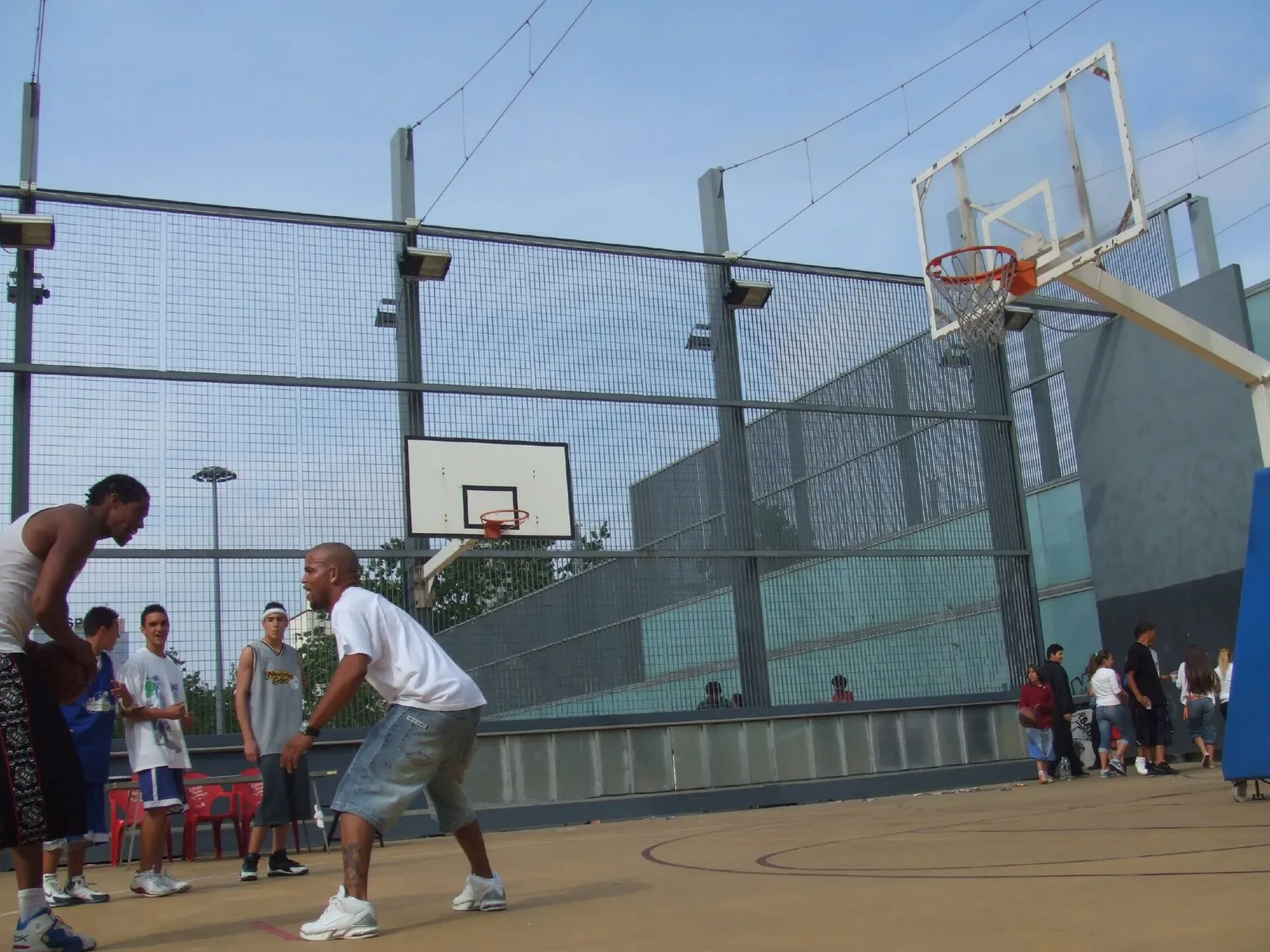 Deux joueurs s'affrontent sur un terrain de basket extérieur