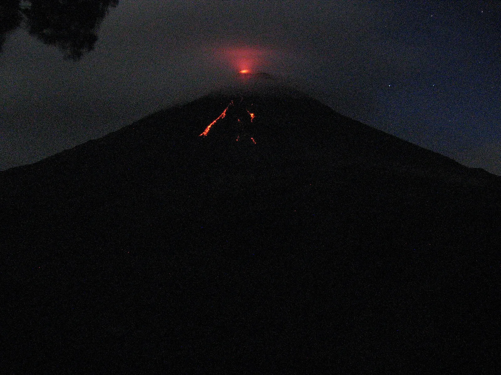 Un volcan en éruption projetant de la lave dans la nuit